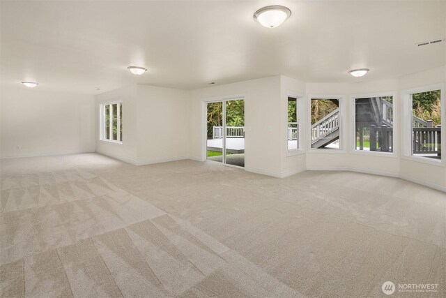 unfurnished room with a wealth of natural light, visible vents, and light colored carpet