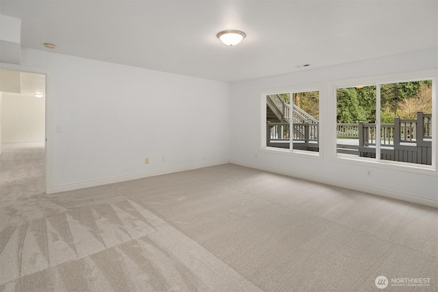 spare room featuring baseboards, light carpet, and visible vents