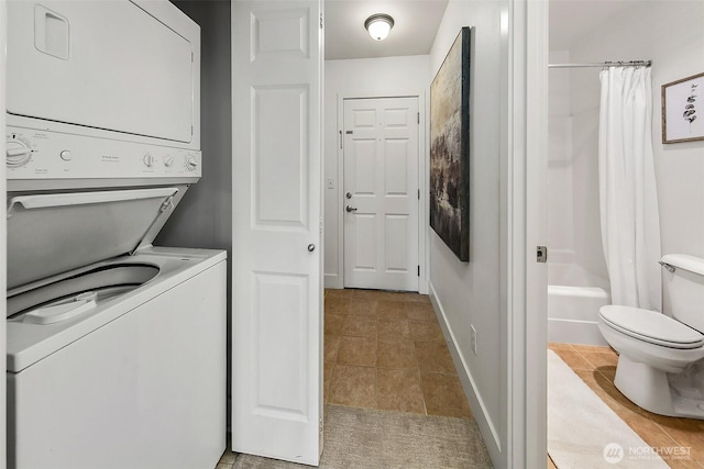 laundry room featuring stacked washer / drying machine, baseboards, laundry area, and tile patterned flooring