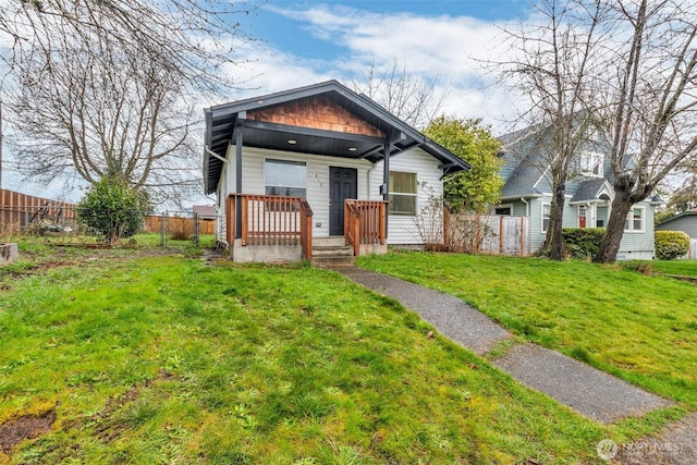 view of front of property with a front yard, fence, and covered porch