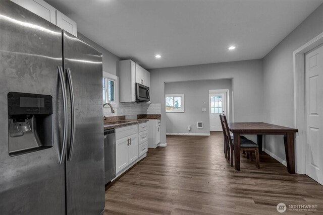 kitchen featuring a sink, dark wood-type flooring, appliances with stainless steel finishes, white cabinetry, and backsplash