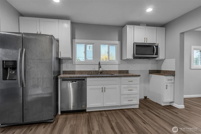 kitchen with dark wood-style floors, white cabinets, appliances with stainless steel finishes, and a sink
