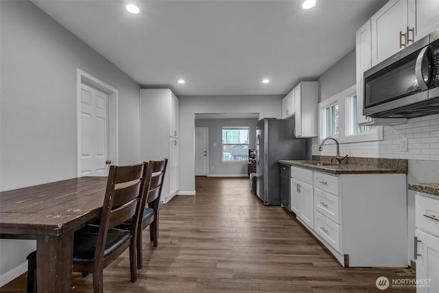 kitchen with recessed lighting, a sink, decorative backsplash, dark wood-type flooring, and stainless steel appliances