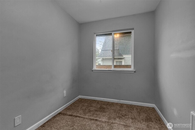 carpeted empty room featuring baseboards