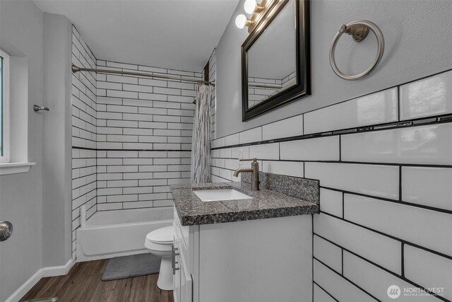 bathroom featuring shower / bathtub combination with curtain, toilet, wood finished floors, tile walls, and vanity