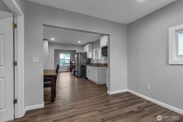 kitchen with baseboards, dark wood-type flooring, appliances with stainless steel finishes, and white cabinetry