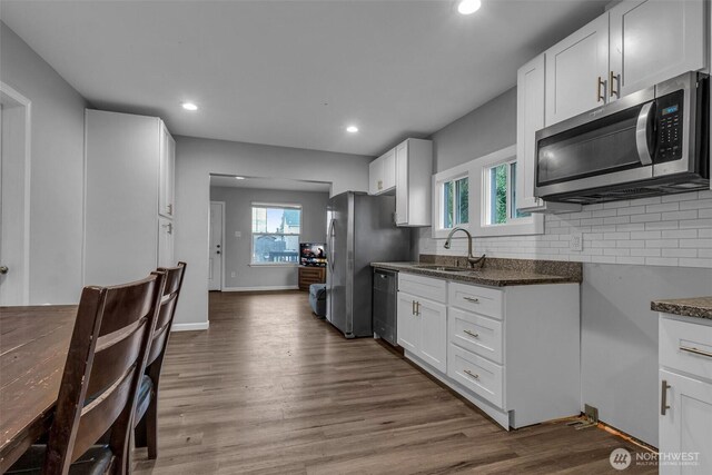 kitchen featuring tasteful backsplash, appliances with stainless steel finishes, white cabinetry, and dark wood-type flooring