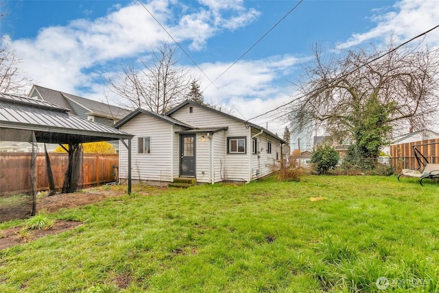 rear view of property with a lawn, entry steps, and a fenced backyard