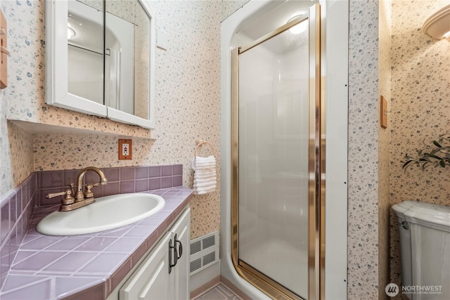 full bath featuring a stall shower, wallpapered walls, and vanity