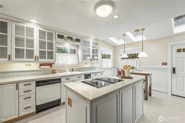 kitchen featuring wallpapered walls, a wainscoted wall, light floors, a skylight, and black electric cooktop