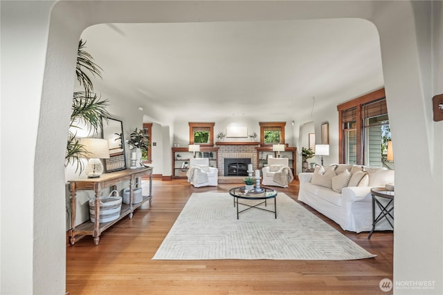 living area with arched walkways, wood finished floors, and a fireplace