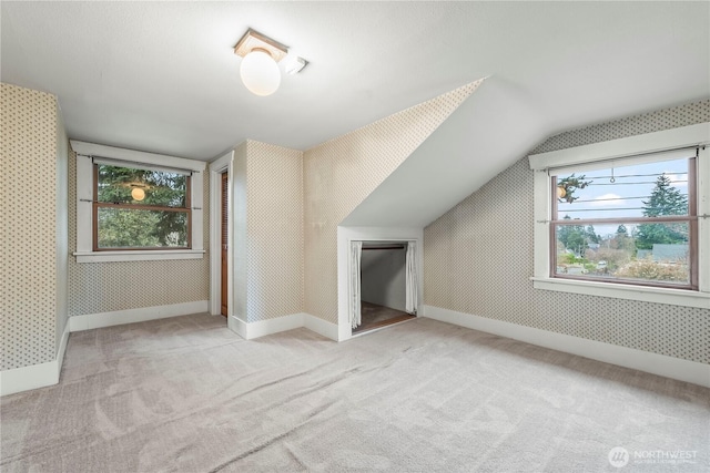 additional living space with wallpapered walls, lofted ceiling, carpet flooring, and baseboards