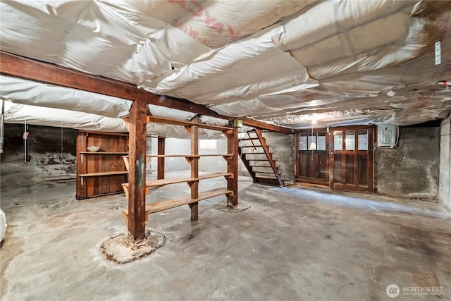 unfinished basement featuring electric panel and stairway