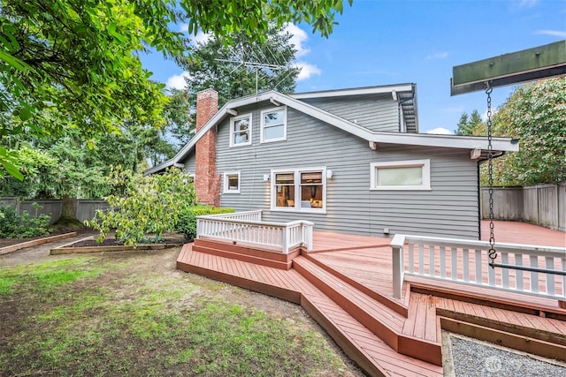 rear view of house with a deck, a vegetable garden, fence, and a chimney