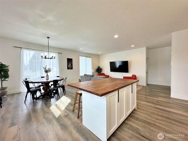 kitchen with wooden counters, plenty of natural light, wood finished floors, and white cabinets