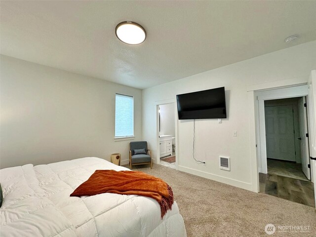 carpeted bedroom with visible vents, connected bathroom, and baseboards