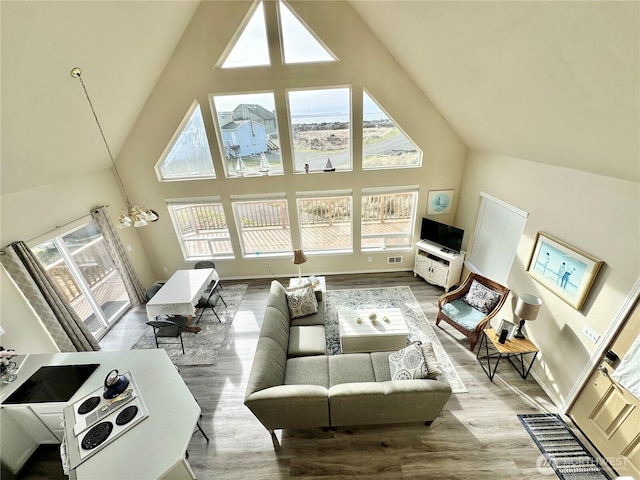 living room featuring high vaulted ceiling, an inviting chandelier, and wood finished floors