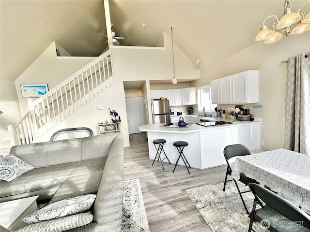 kitchen with light wood finished floors, a kitchen breakfast bar, freestanding refrigerator, white cabinetry, and a sink