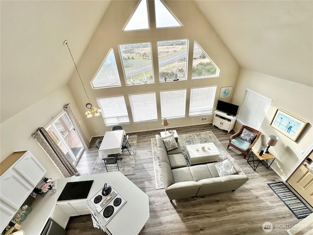 living area featuring high vaulted ceiling, an inviting chandelier, and wood finished floors