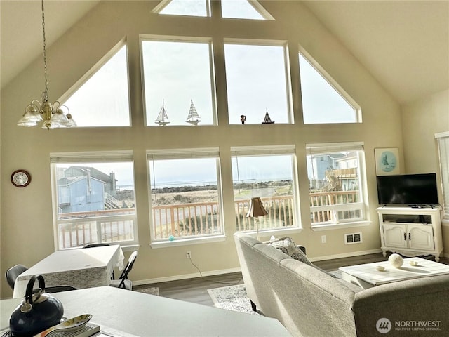 living area with visible vents, wood finished floors, baseboards, and a chandelier