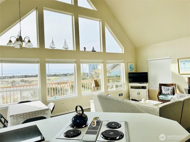 interior space with open floor plan, a healthy amount of sunlight, high vaulted ceiling, and an inviting chandelier