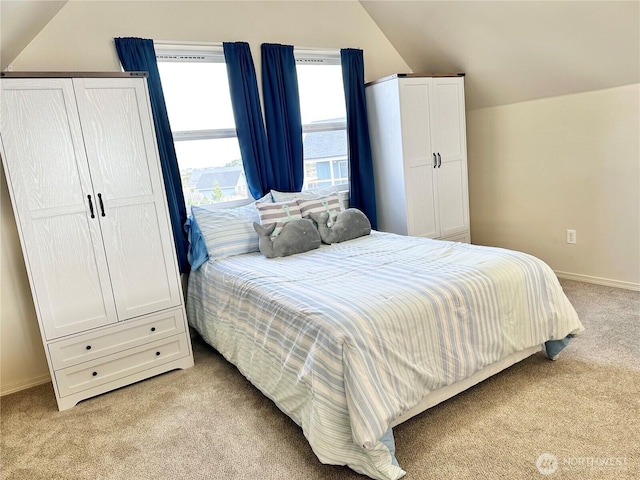 bedroom with lofted ceiling, baseboards, and light carpet