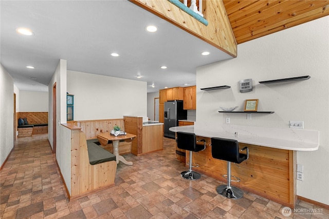 kitchen with recessed lighting, stone finish floor, black refrigerator with ice dispenser, and light countertops