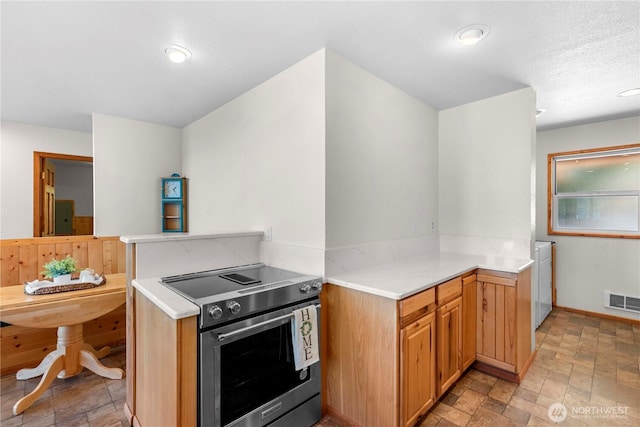 kitchen with baseboards, visible vents, washer / clothes dryer, stone finish floor, and electric stove