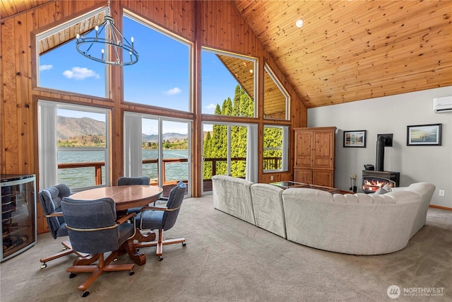 living area with high vaulted ceiling, wine cooler, a water and mountain view, a chandelier, and a wood stove