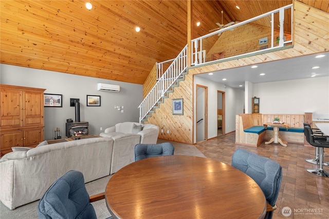 dining area featuring stairway, wood ceiling, a wood stove, high vaulted ceiling, and a wall mounted AC