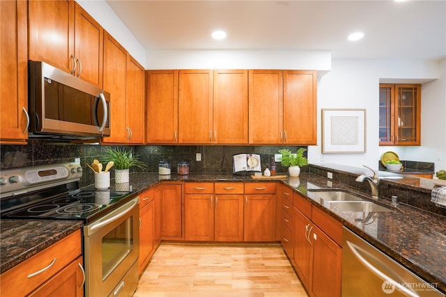 kitchen featuring brown cabinets, appliances with stainless steel finishes, light wood-type flooring, and a sink