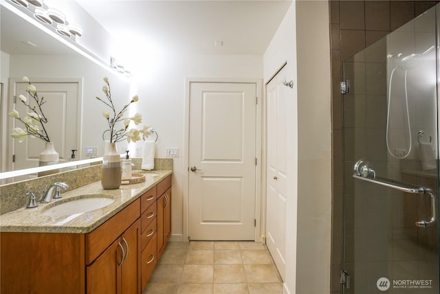 bathroom featuring tile patterned flooring, double vanity, a shower stall, and a sink