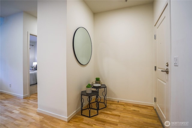 corridor featuring light wood-style flooring and baseboards