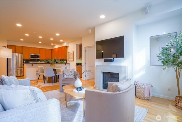 living room featuring a glass covered fireplace, recessed lighting, and light wood-style floors