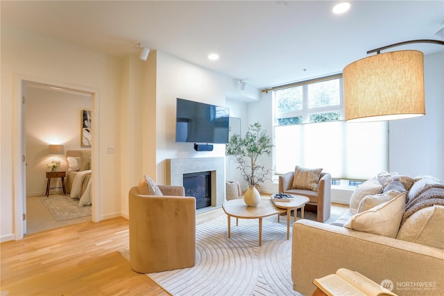 living room with a glass covered fireplace, baseboards, wood finished floors, and recessed lighting