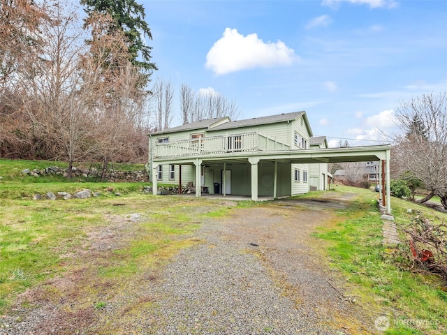 rear view of property with a carport, gravel driveway, and a deck