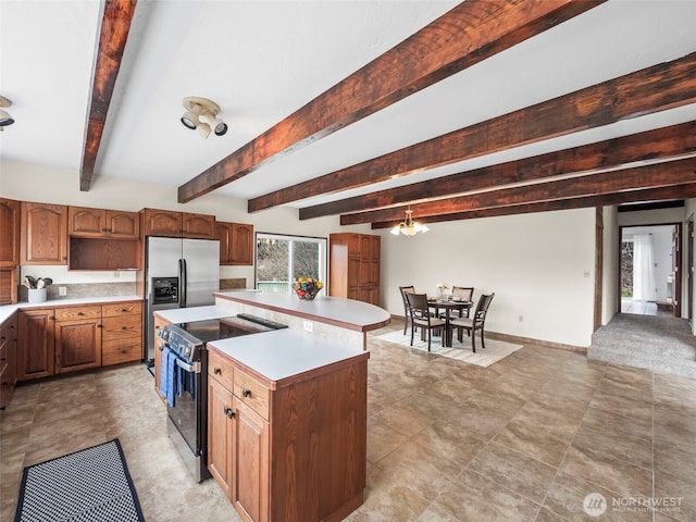 kitchen with a center island, light countertops, range with electric stovetop, a notable chandelier, and stainless steel fridge