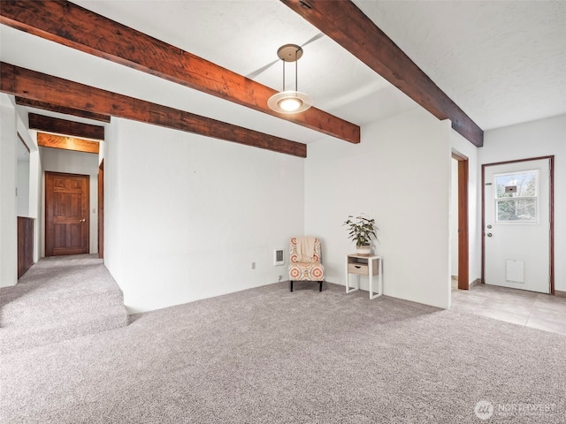 unfurnished room with beam ceiling and carpet flooring