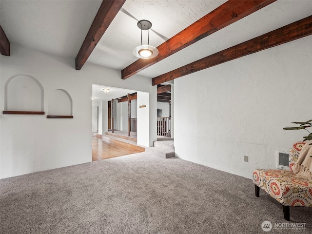 interior space featuring beamed ceiling, carpet flooring, and a textured wall