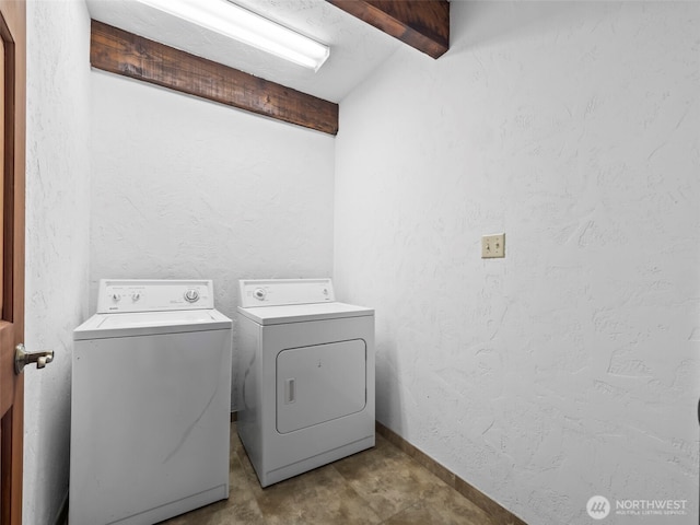 clothes washing area with laundry area, a textured wall, independent washer and dryer, and baseboards