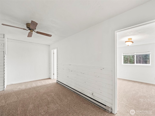 spare room featuring a baseboard heating unit, baseboards, carpet floors, and ceiling fan