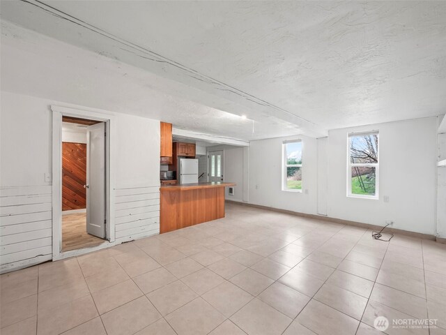 unfurnished living room featuring light tile patterned floors and a textured ceiling