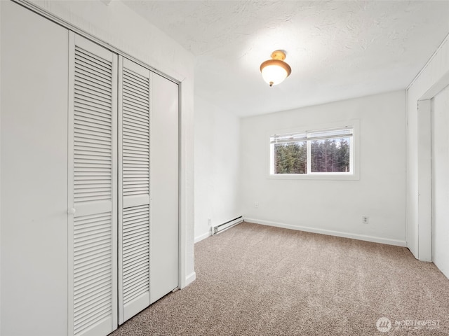 unfurnished bedroom with a closet, carpet flooring, a baseboard heating unit, and baseboards