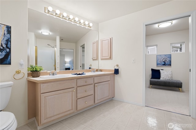 bathroom with double vanity, toilet, and a sink