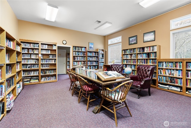 carpeted office space with bookshelves and visible vents