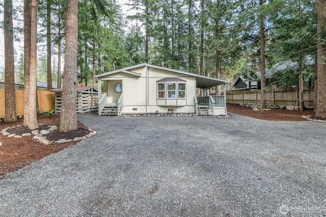 manufactured / mobile home featuring gravel driveway, fence, and crawl space