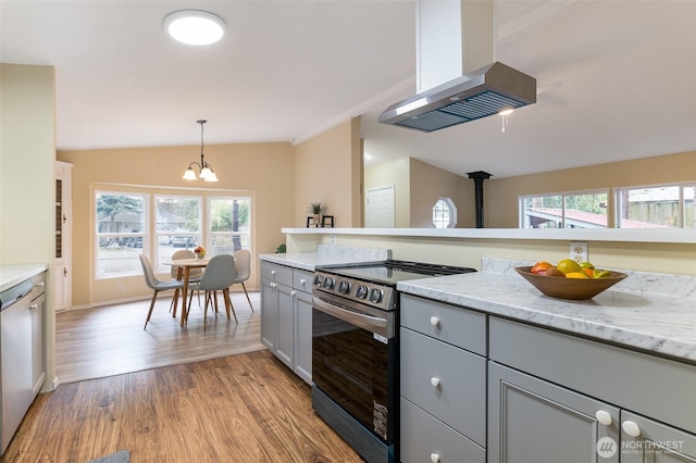 kitchen featuring a notable chandelier, gray cabinetry, electric stove, light wood-style floors, and wall chimney exhaust hood