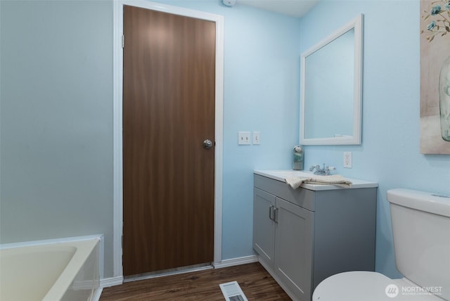 bathroom with vanity, toilet, wood finished floors, and visible vents