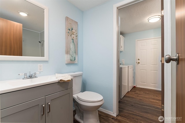 bathroom with vanity, wood finished floors, baseboards, toilet, and washing machine and dryer