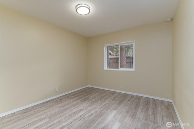 unfurnished room with light wood-type flooring and baseboards